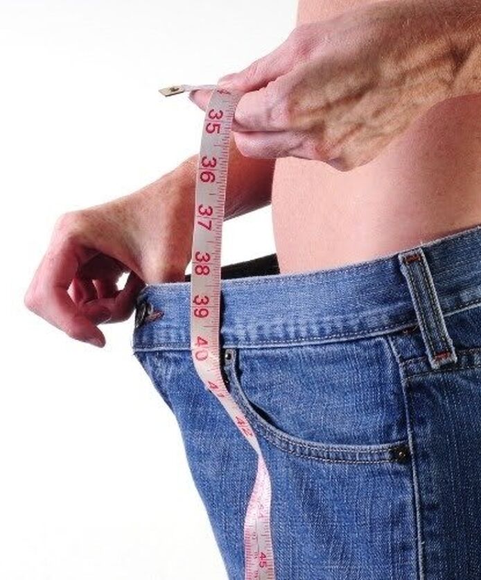 Person measuring waist after weight loss journey.