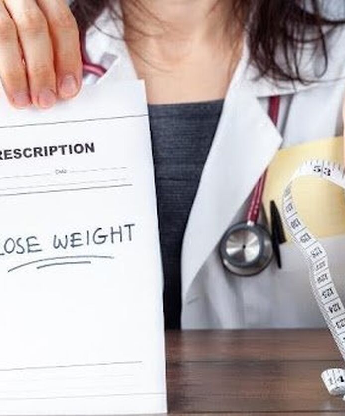 Doctor holding weight loss prescription and measuring tape.