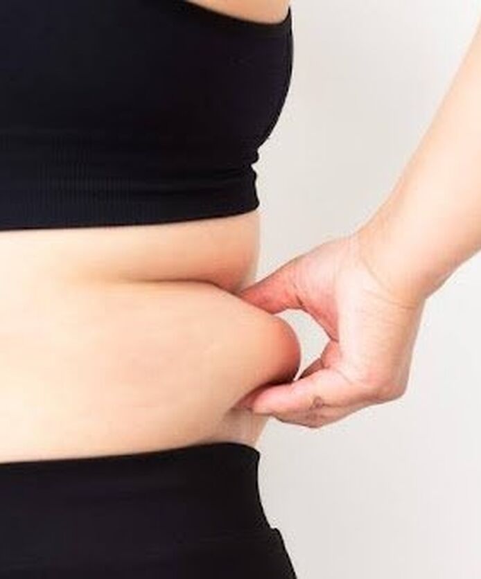 Close-up of person pinching belly fat.