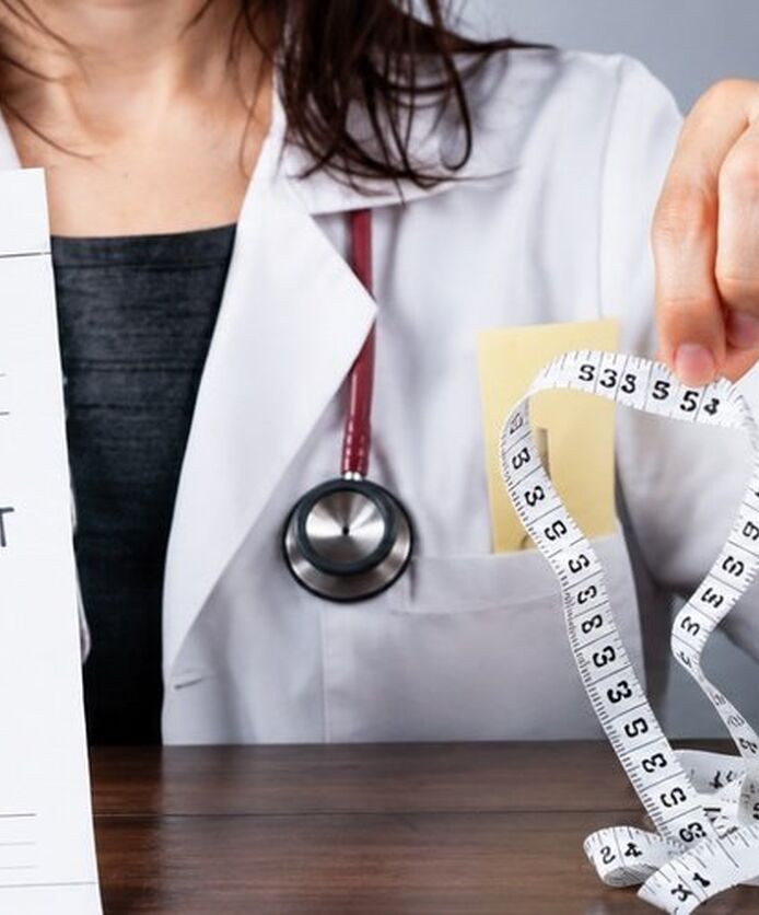 Doctor holding weight loss prescription and measuring tape.