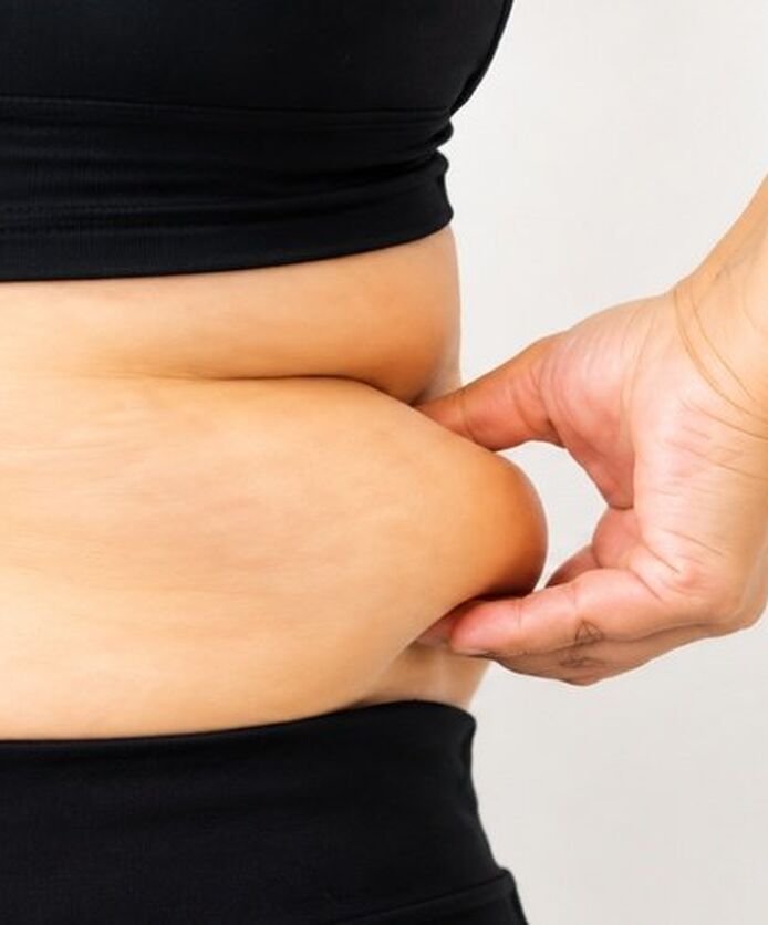 Close-up of person pinching belly fat