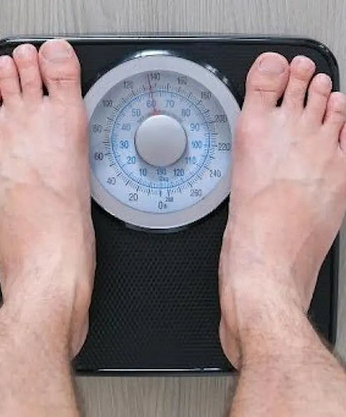 Person checking body weight on a weighing scale.