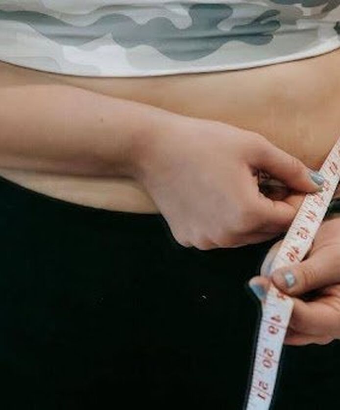 Woman measuring her waist during weight loss.