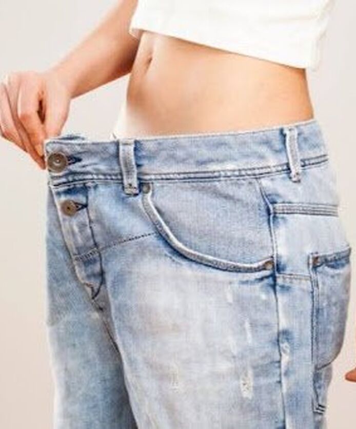 Woman showing weight loss with loose-fitting jeans.