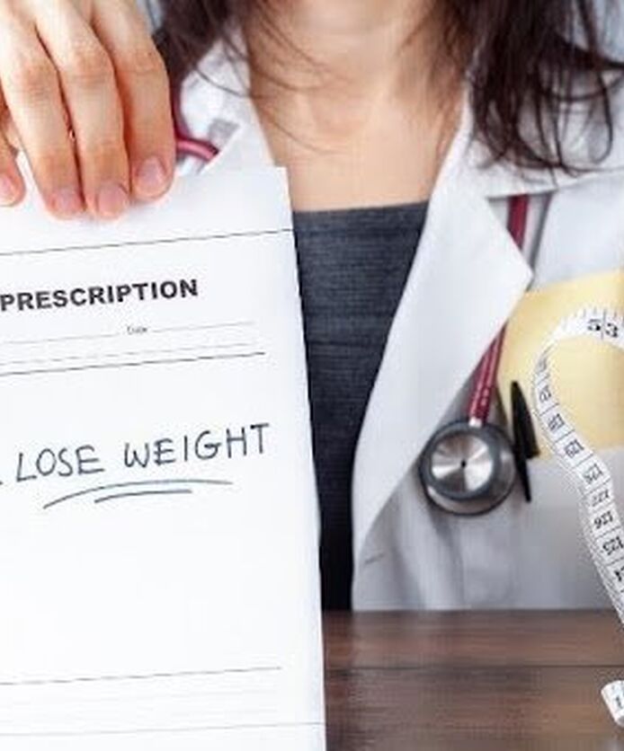 Doctor holding a weight loss prescription and measuring tape representing medical weight management treatment.
