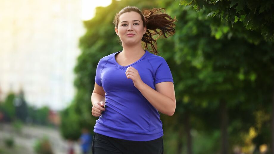 A woman jogs outside under the shade of some trees.
