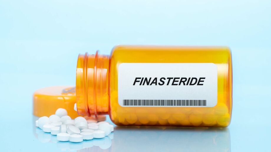 A bottle of finasteride pills on its side with the pills spilling out.