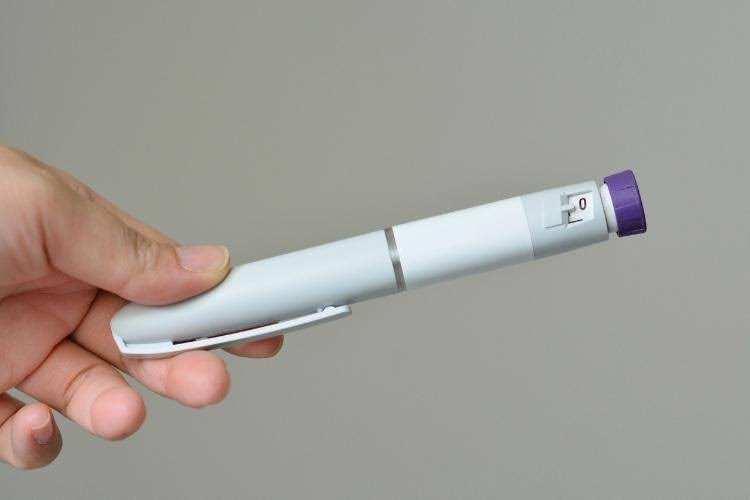 Hand holding weight loss injection pen medication.