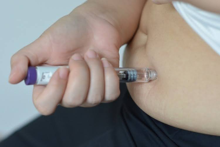 Person injecting weight loss medication into stomach.