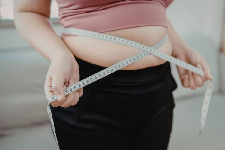 Measuring waist size during weight loss progress.