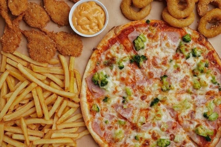 Pizza fries and fried chicken high calorie fast food meal.