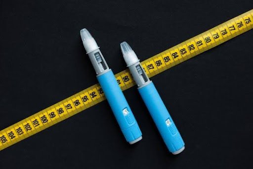 Injectable weight loss pens next to a measuring tape.