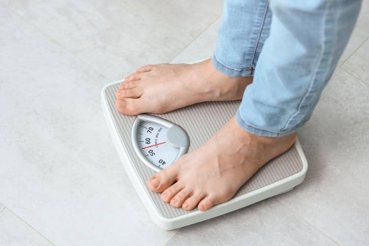 Person standing on weighing scale for weight tracking.