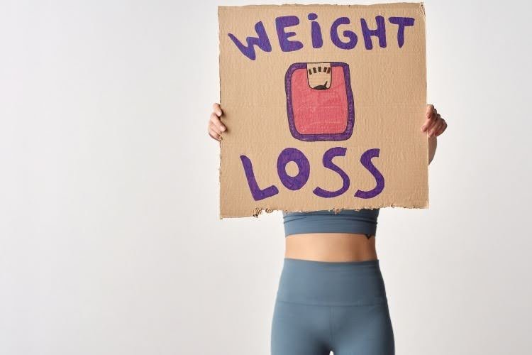 Person holding a weight loss sign representing the benefits of Mounjaro treatment.